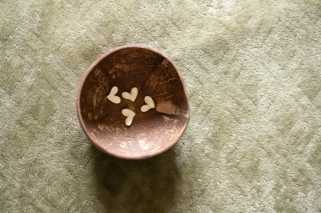 Petit bol en noix de coco avec des cœurs, posé sur un tissu vert