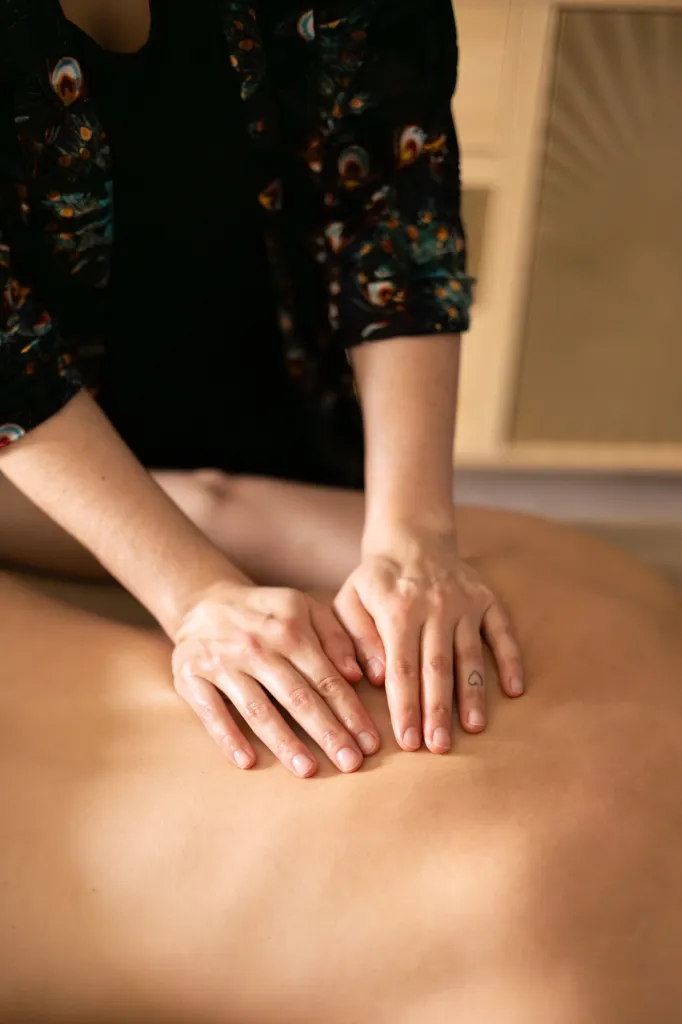 Mains de Sarah posées sur le dos d'une cliente pendant un massage